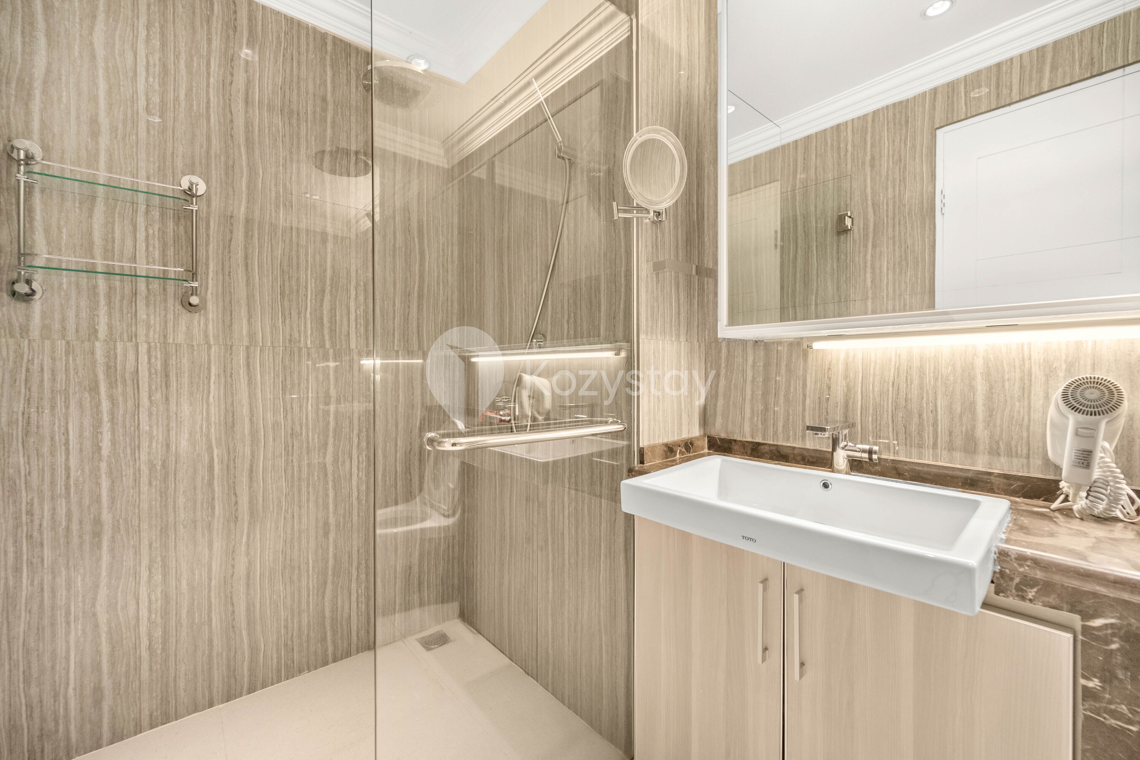 Un baño moderno con cabina de ducha de vidrio, un lavabo blanco y un secador de pelo sobre la encimera.