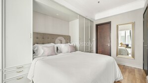 A bedroom with a large bed, a wardrobe, and a mirror.