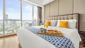 A modern hotel room with a large bed, a breakfast tray, and a city view through large windows. - BUNGALOW by Kozystay (Jakarta)