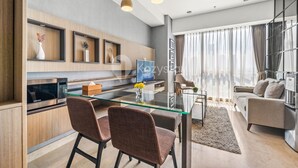 A modern living room with a glass dining table, two chairs, a sofa, and a TV. - QUARTER by Kozystay (Jakarta)
