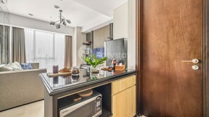 A modern kitchen with a built-in microwave, wooden cabinets, and a wooden door. - LONDON by Kozystay (Jakarta)