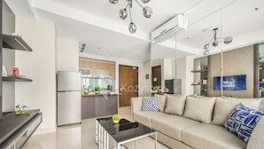 A modern living room with a sofa, coffee table, and kitchen in the background. - LONDON by Kozystay (Jakarta)
