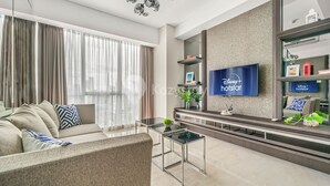 A modern living room with a sofa, coffee table, and TV. - LONDON by Kozystay (Jakarta)