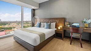 Une chambre d’hôtel moderne, dotée d’un grand lit, d’un bureau et offrant une vue sur la ville.