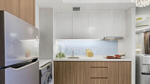 Une cuisine moderne dotée d’appareils électroménagers en acier inoxydable, de meubles de rangement en bois et d’un lave-linge encastré.