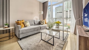 A modern living room with a grey sofa, a round coffee table, and a flat-screen TV. - MAPLE by Kozystay (Jakarta)