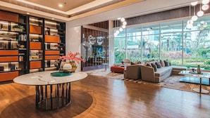 A modern living room with a large bookshelf, a round coffee table, and a sofa facing large windows. - MAPLE by Kozystay (Jakarta)