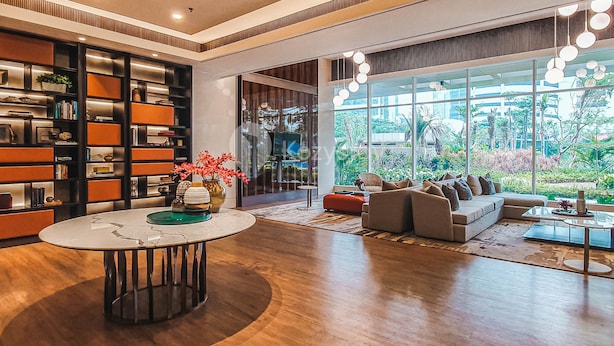 A modern living room with a large bookshelf, a round coffee table, and a sofa facing large windows. - CEDAR by Kozystay (Jakarta)