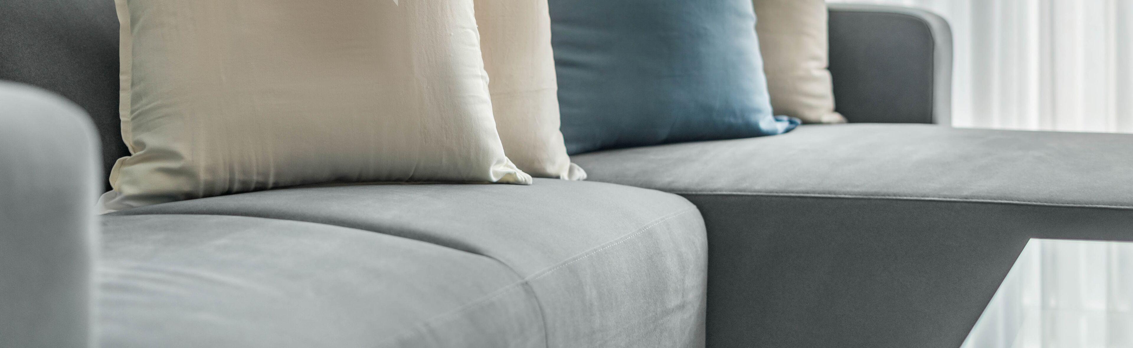 A close-up of a grey sofa with multiple cushions.