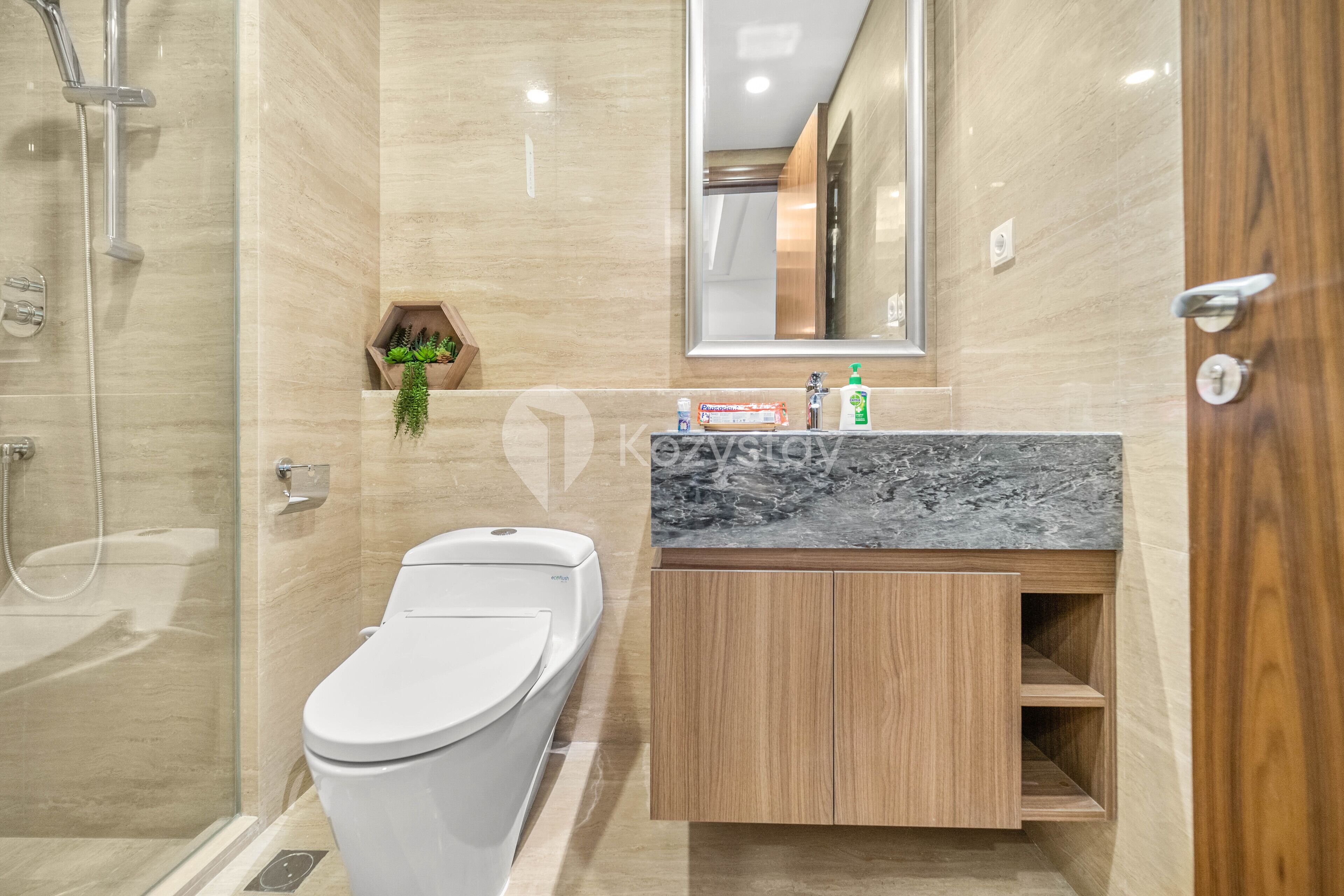 A modern bathroom with a glass-enclosed shower, a toilet, and a vanity with a marble countertop.