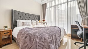 A modern hotel room with a large bed, a desk, and a chair. - HAVEN by Kozystay (Jakarta)