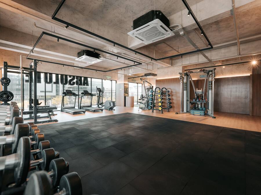 A spacious gym with various exercise equipment, large windows, and a clean, modern design.