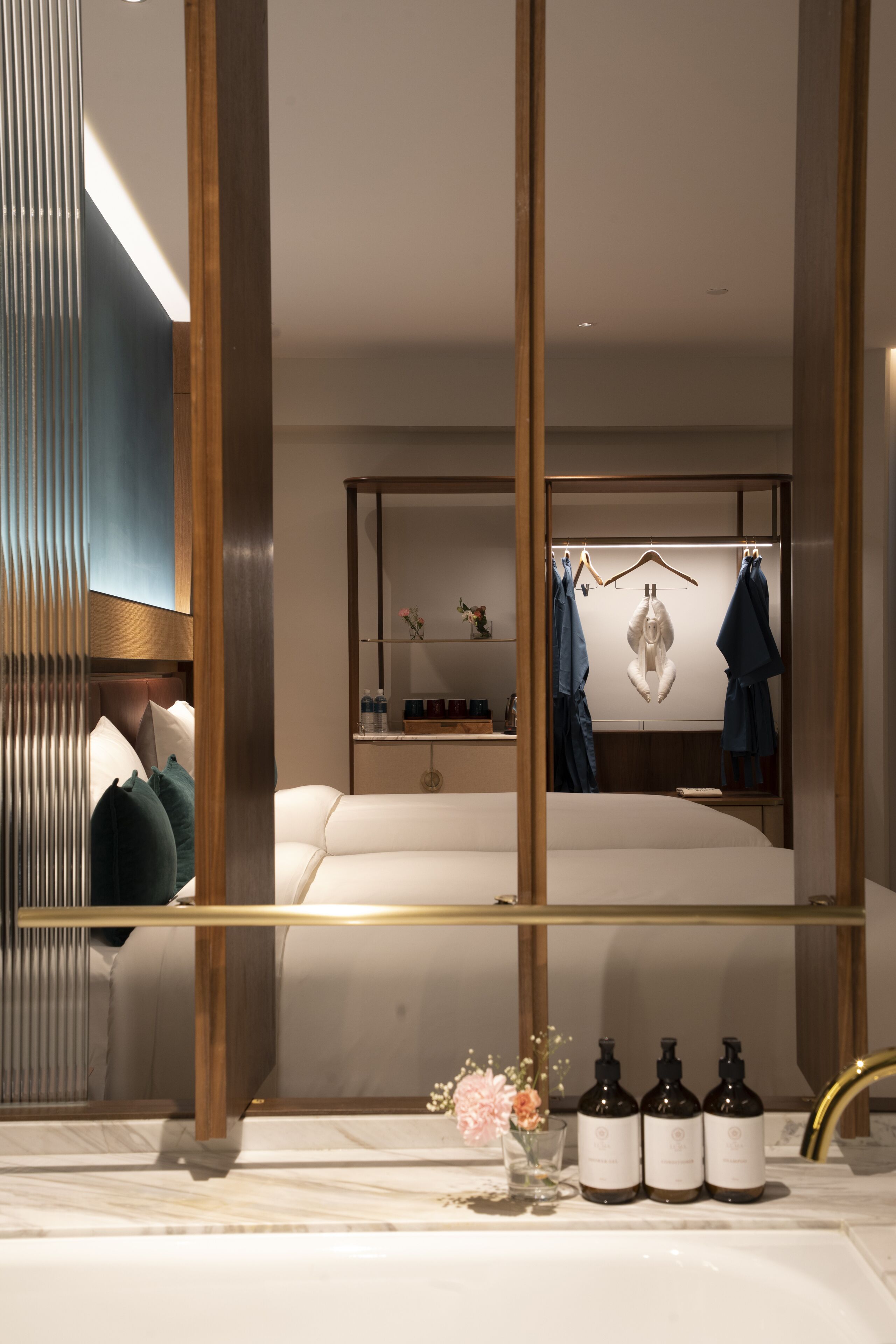 A modern bathroom with a large mirror, a white bathtub, and a vanity with toiletries.