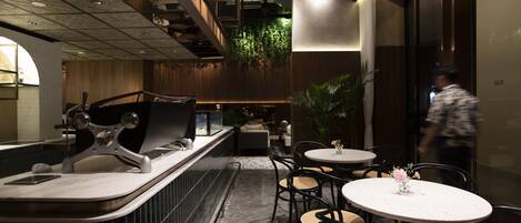 A modern restaurant with a bar area, round tables, and chairs.