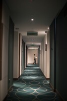 Pasillo de hotel con alfombra estampada, puertas a ambos lados y señales indicando la salida.