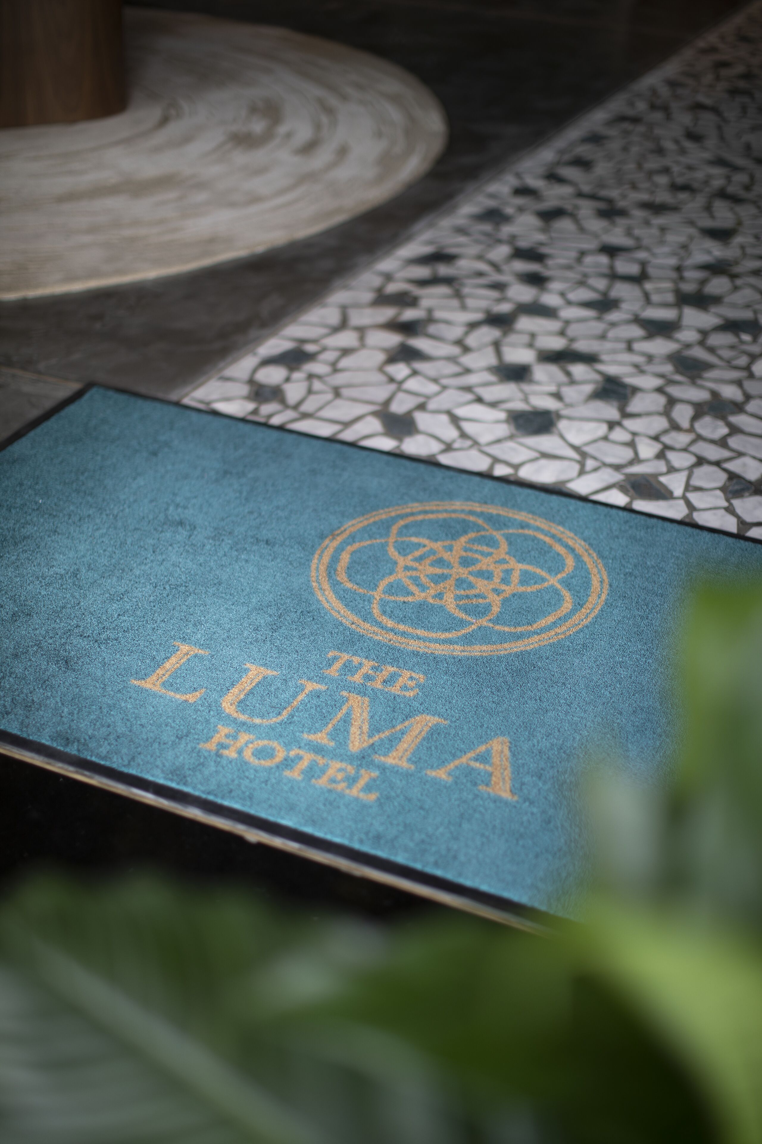 Un tappetino blu con la scritta "The Luma Hotel" e un logo.