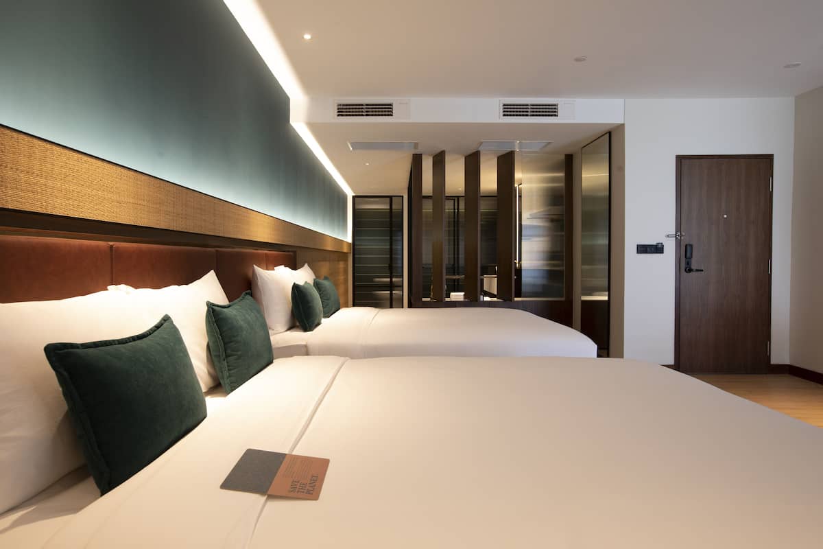 A modern hotel room with a large bed, a wooden headboard, and a walk-in closet with a sliding door.