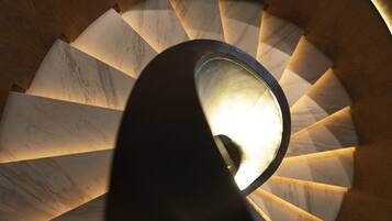 Uma escadaria em espiral com um candelabro no centro.