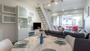 Un comedor moderno con una mesa redonda dispuesta para cuatro personas, una escalera y vistas al exterior.