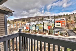 Un barrio residencial con casas coloridas, cielo despejado y un telón de fondo montañoso.