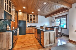 Une cuisine avec des meubles en bois, un réfrigérateur noir et un grand îlot central doté d’un évier.