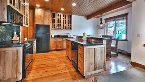 Una cocina con armarios de madera, un refrigerador negro y una isla grande con un lavamanos.