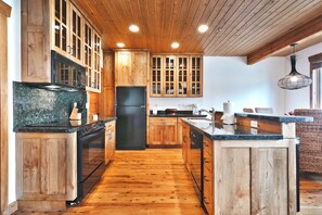 Une cuisine avec des meubles de rangement en bois, un réfrigérateur noir et un plan de travail en granit.
