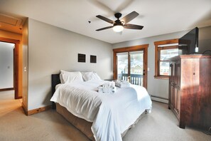 Une chambre à coucher avec un lit, un ventilateur de plafond, une fenêtre et une armoire en bois.