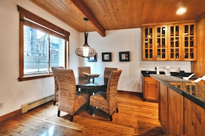 Un coin repas avec une table et des chaises en bois, un luminaire suspendu et des armoires en bois.