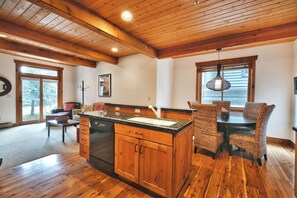 A spacious kitchen with wooden cabinets, a central island, and a dining area with wicker chairs.