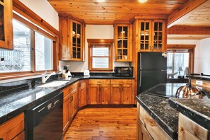 Una cocina con armarios de madera, un refrigerador negro y una encimera de granito.