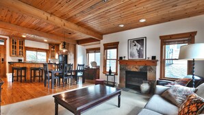 A spacious living room with a wooden ceiling, a fireplace, a dining area with wooden cabinets, and a large sofa with patterned cushions. - On Deer Valley Drive - Easy Walk/Shuttle to Skiing and Main St. (Park City)