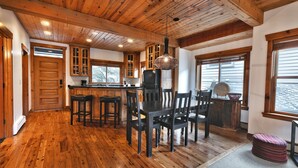 A spacious kitchen with wooden floors, a dining area with dark wooden chairs, and a large island with bar stools. - On Deer Valley Drive - Easy Walk/Shuttle to Skiing and Main St. (Park City)