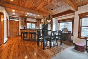 Kitchen features a central island with bar stools, refrigerator, and hanging light fixture.