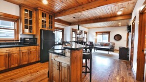 A spacious kitchen with wooden cabinets, a central island, and a dining area with a sofa and chairs. - On Deer Valley Drive - Easy Walk/Shuttle to Skiing and Main St. (Park City)