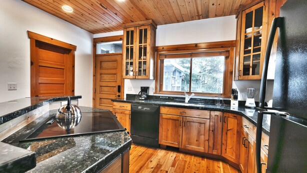 A kitchen with wooden cabinets, a black refrigerator, and a granite countertop. - On Deer Valley Drive - Easy Walk/Shuttle to Skiing and Main St. (Park City)