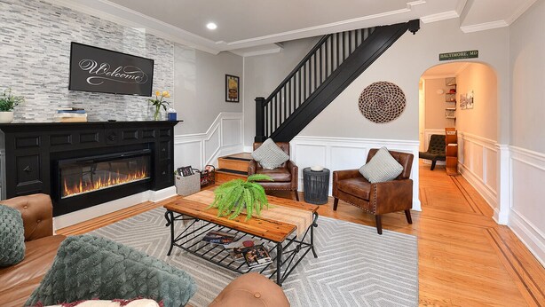 Una sala de estar con chimenea, sillones de cuero, una mesa de centro y una escalera.
