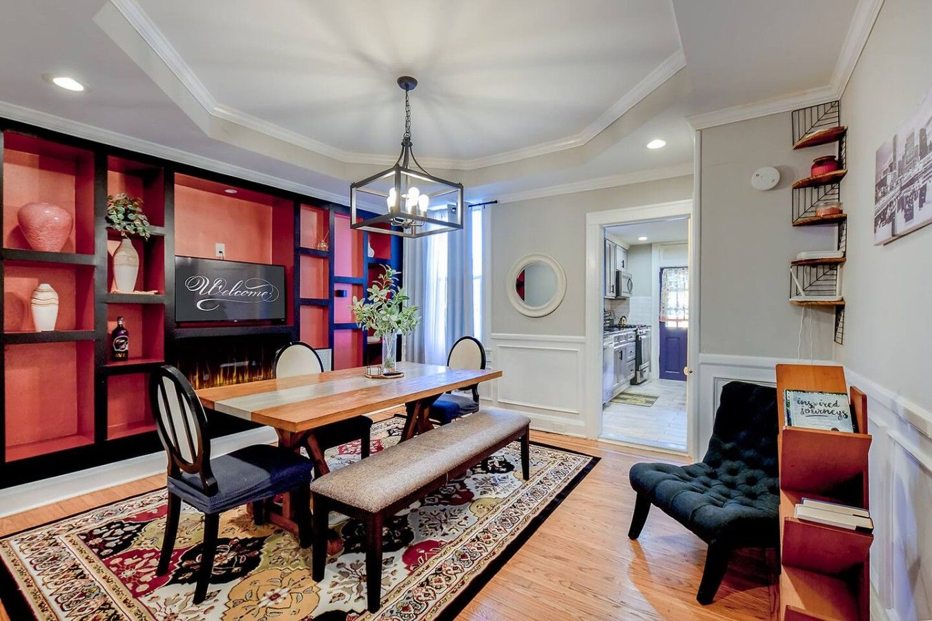 A dining area with a wooden table, chairs, a bench, a chandelier, and a TV on the wall.