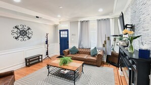 Una sala de estar con un sofá, una mesa de centro y un televisor montado en la pared.