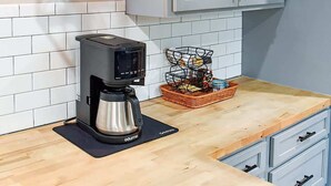 Una cocina moderna con cafetera, una cesta de vajilla y luces colgantes.