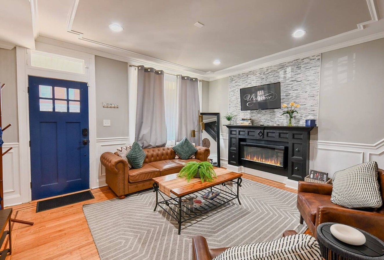 A living room with a fireplace, a blue door, and a sofa with cushions.
