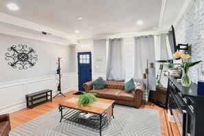 Una sala de estar con un sofá, una mesa de centro y una televisión sobre una pared de ladrillo.