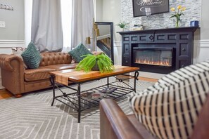 A living room with a fireplace, a sofa, a coffee table with decorative items, and a striped chair.
