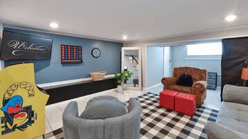 A living room with a checkered floor, a television, a dartboard, and a welcome sign.