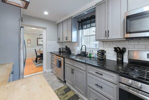 A modern kitchen with white cabinets, a stainless steel stove, and a black countertop.