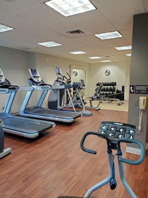 A gym with treadmills, exercise bikes, and a wall-mounted emergency telephone.