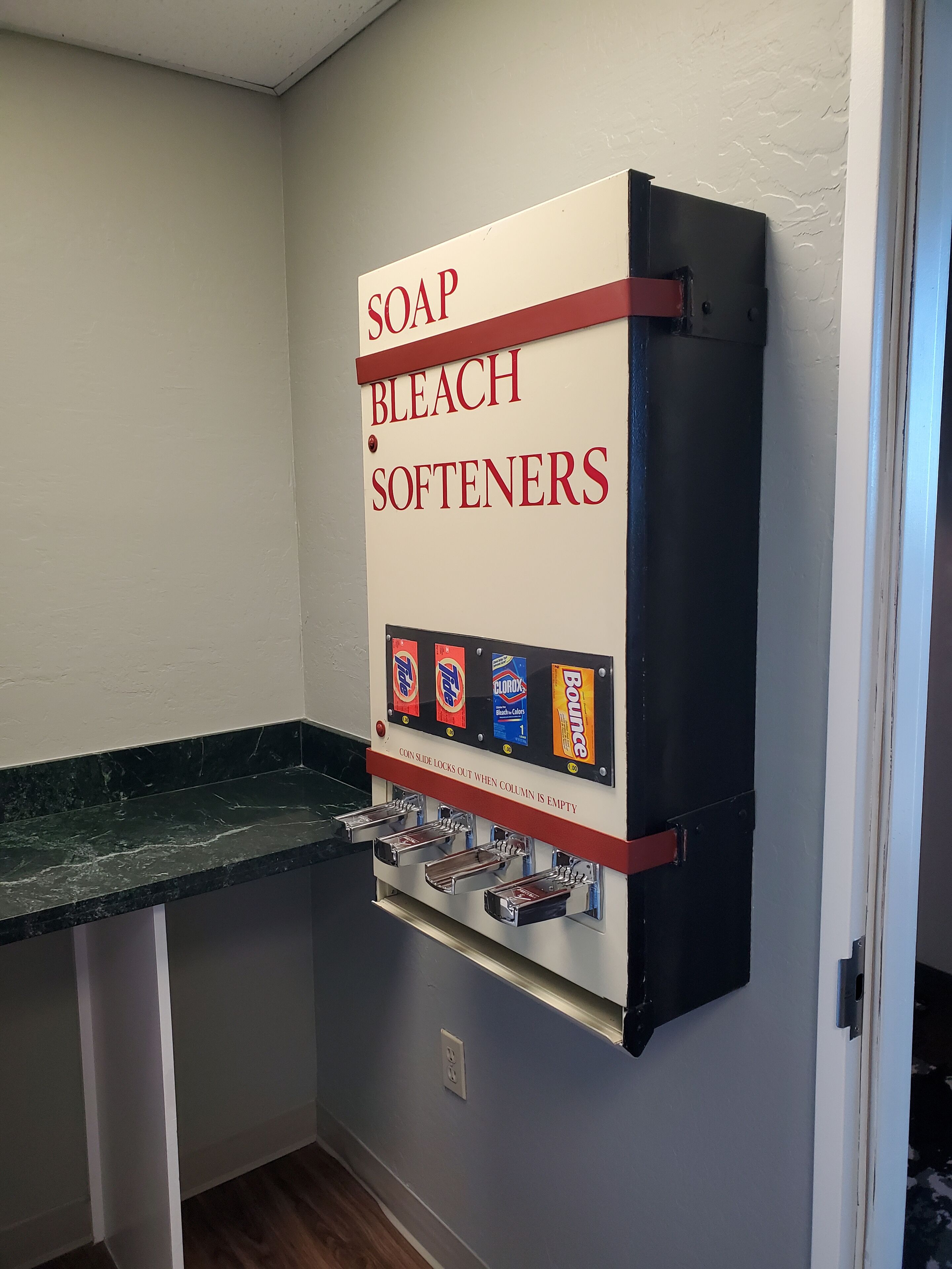 A wall-mounted dispenser with soap, bleach, and softeners.