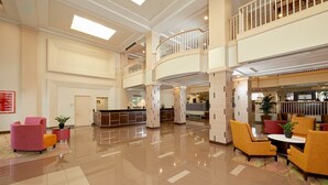 Eine großzügige Lobby mit Empfangsschalter, einer Sitzecke und einem Balkon im zweiten Stock.