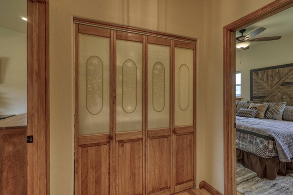 A bedroom with a wooden wardrobe, a bed with a plaid bedspread, and a ceiling fan.