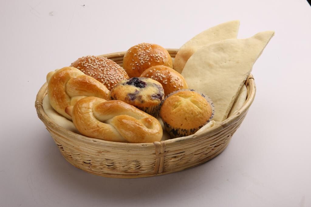 Una cesta con diferentes tipos de pan, incluyendo panecillos y pan plano.